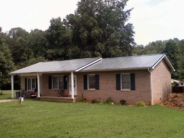 Gray metal roof on a brick ranch house with a side carport in Warsaw