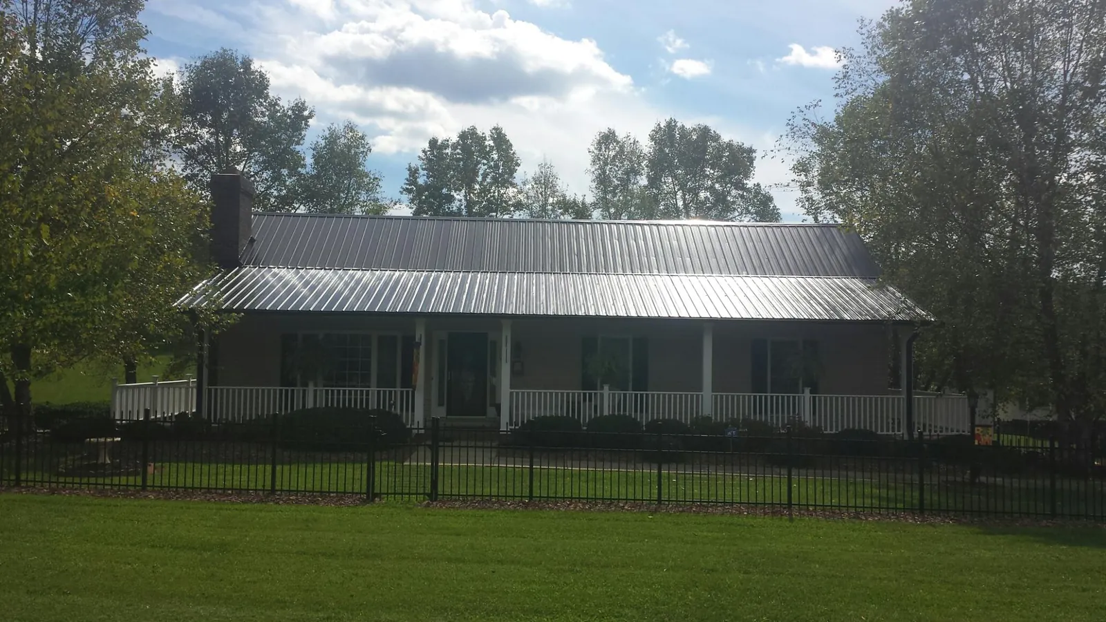 Gray metal roof on a brick ranch with a full width front porch — Gutter Guard Installation work by our crew in Warsaw